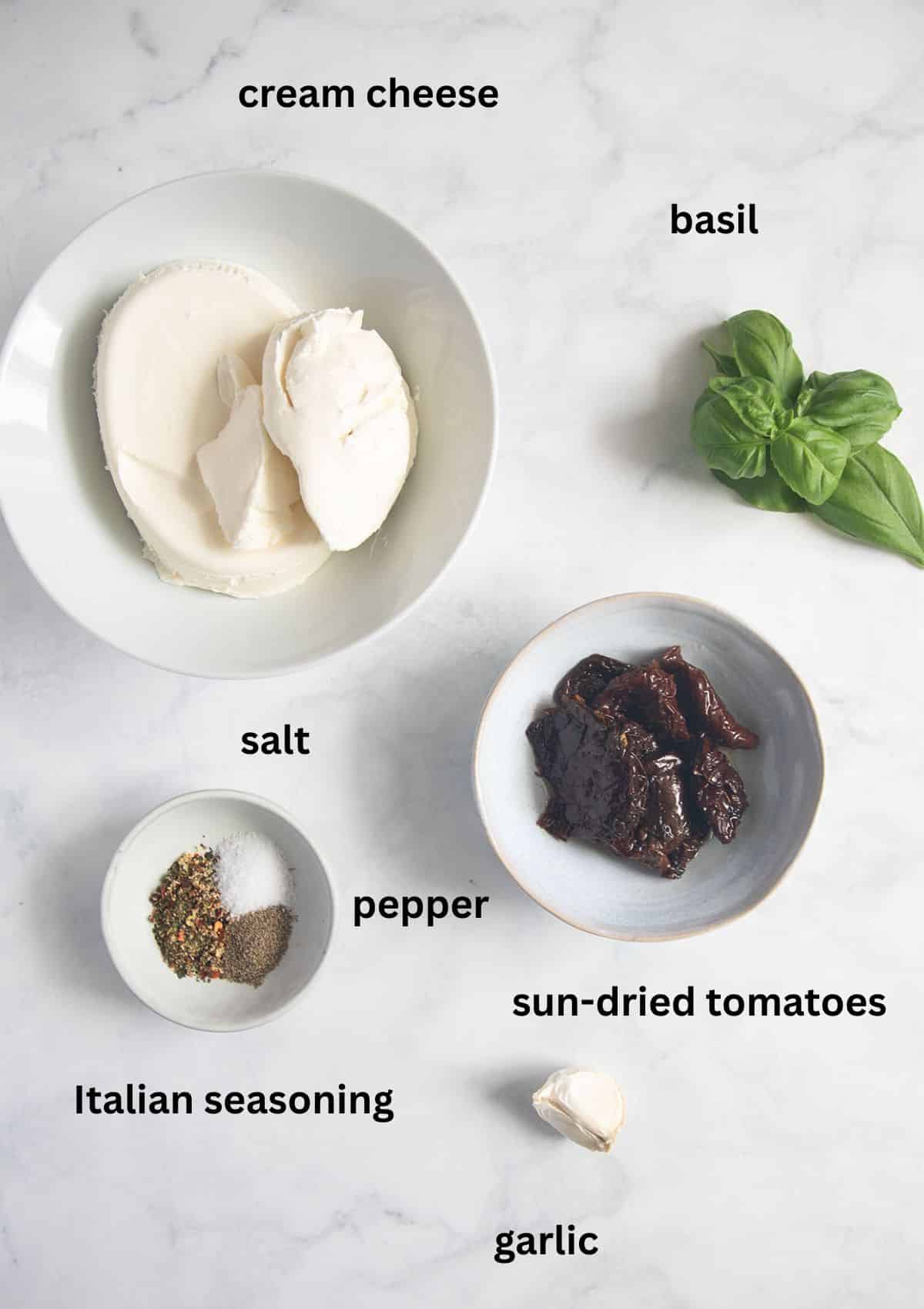 Sun-dried tomatoes, cream cheese, garlic, basil, and Italian seasoning measured and ready to make a creamy sun-dried tomato cream cheese dip.