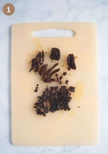 Finely chopped sun-dried tomatoes on a cutting board, ready to be added to the dip.