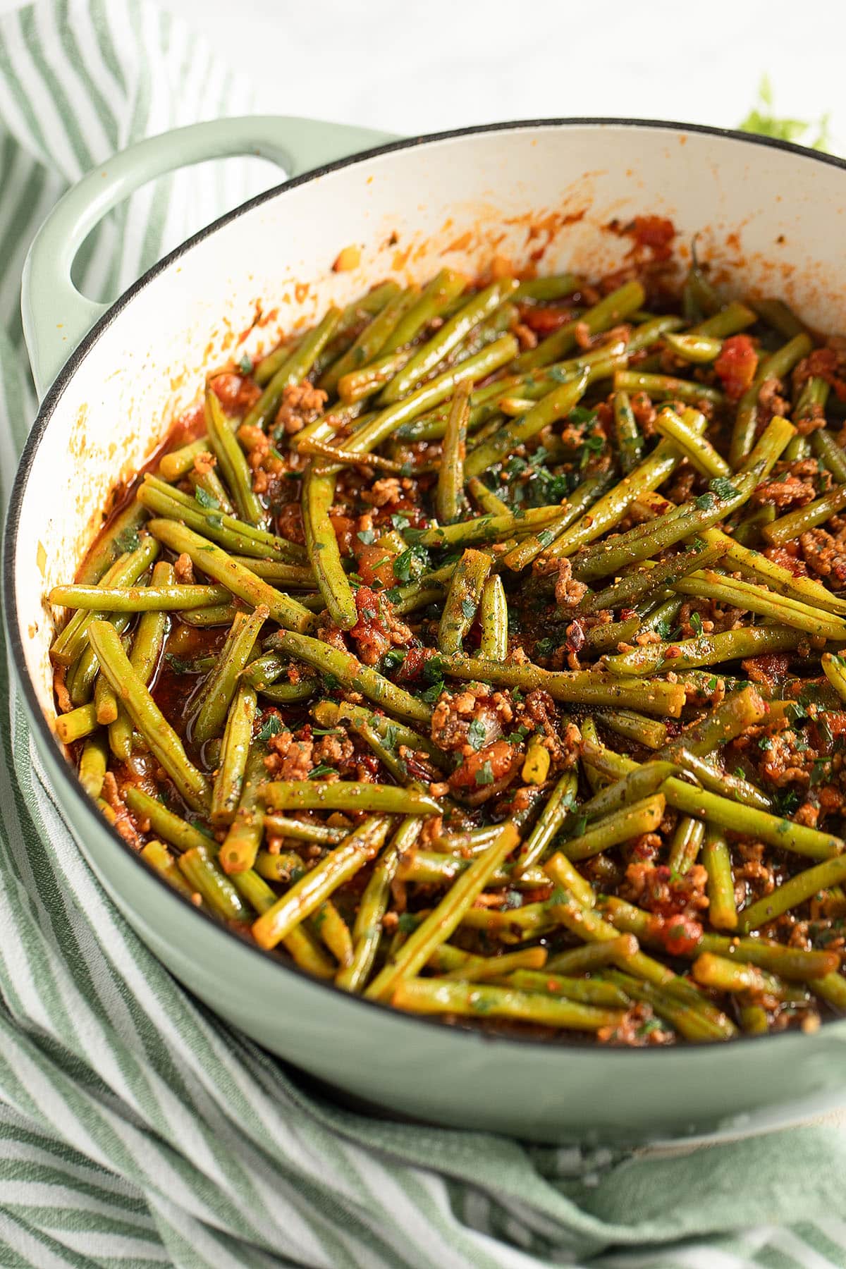ragu with ground beef and green beans in tomato sauce in a large pot.