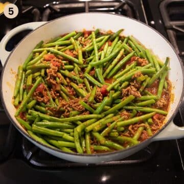 uncooked green bean and beef ragu in a dutch oven on the stove.