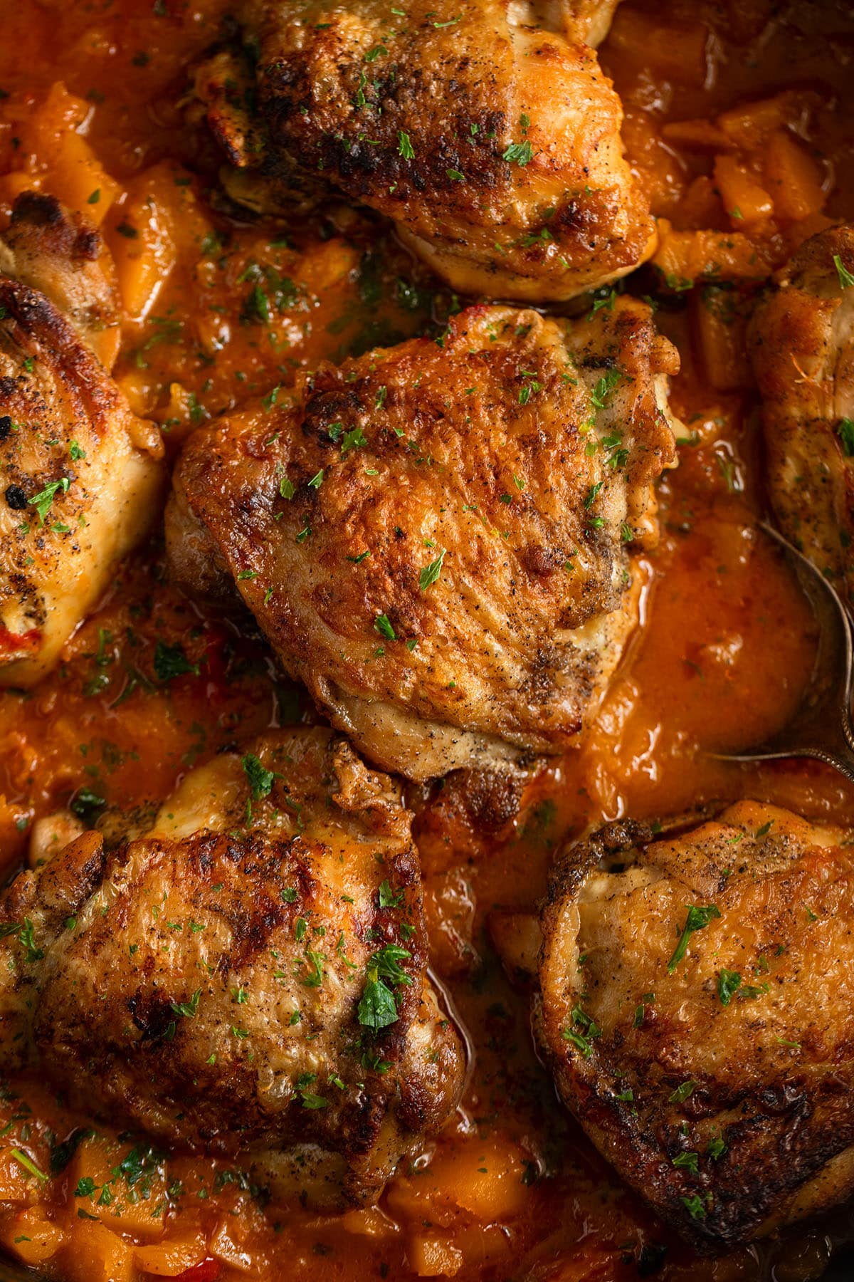 butternut chicken thighs with thick sauce and sprinkled with parsley.