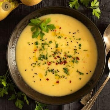 blended parsnip, pear and potato soup sprinkled with herbs in a bowl.