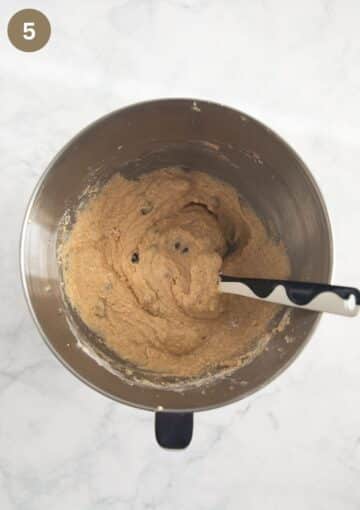 batter for irish coffee cake with whiskey and raisins in a bowl with a spatula in it.