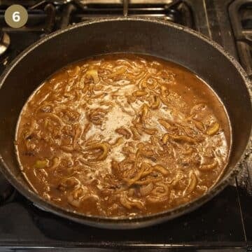 onion gravy with guinness and stock simmering in a skillet.
