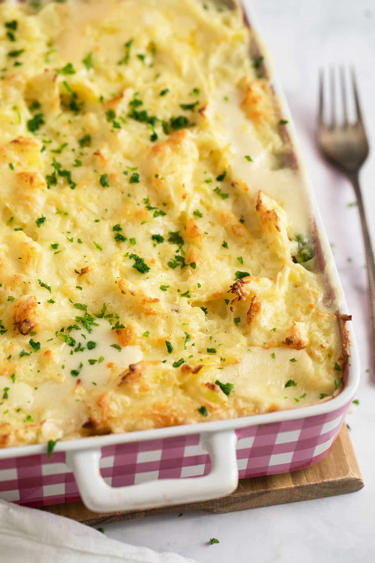 irish fish pie with mashed potatoes in a baking dish with a fork beside it.