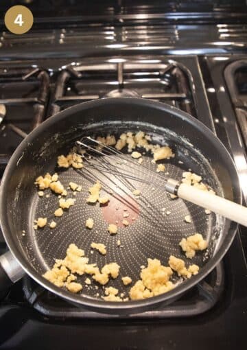 whisking flour into melted butter in a saucepan to make white sauce for fish pie.