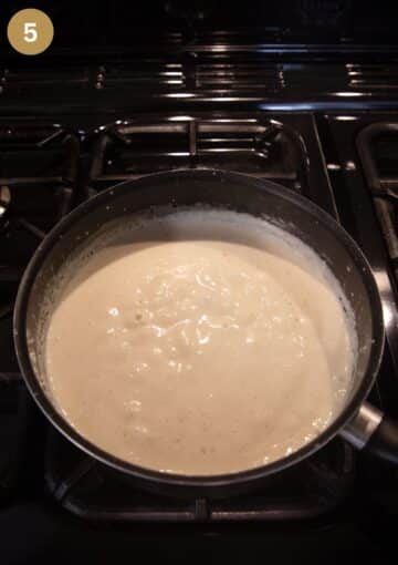 thickened white sauce for making fish pie in a saucepan.
