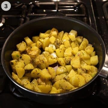 adding dried herbs to potato cubes in a saucepan.