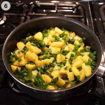 adding chopped green onions to potatoes in a saucepan.