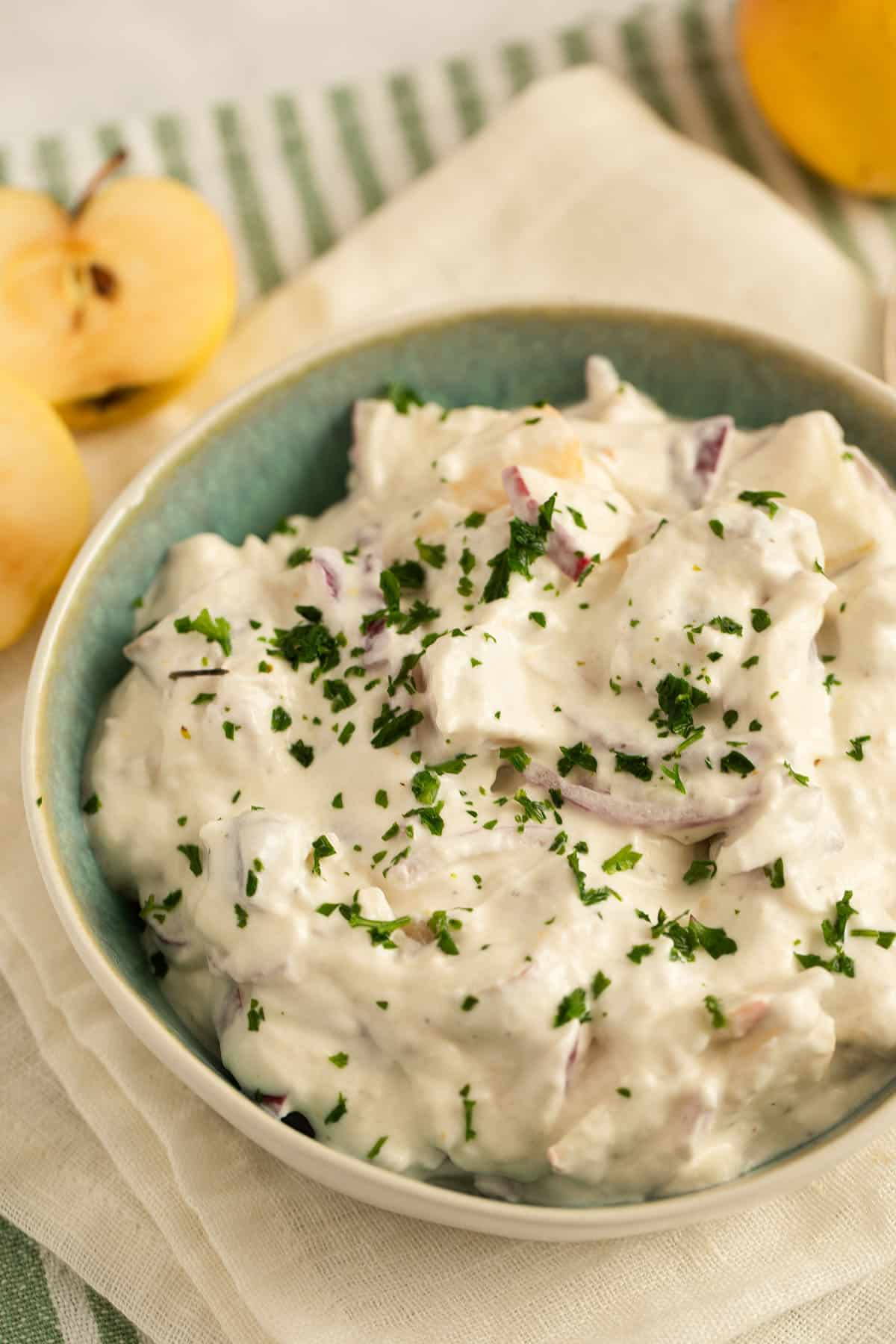 creamy herring salad with apples and onions in a bowl.