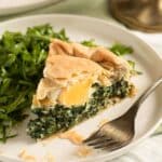 italian spinach pie with egg inside or torta pasqualina sliced on a plate.