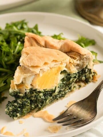 italian spinach pie with egg inside or torta pasqualina sliced on a plate.