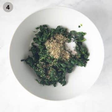 chopped spinach mixed with salt, pepper, and marjoram for making pie filling in a bowl.