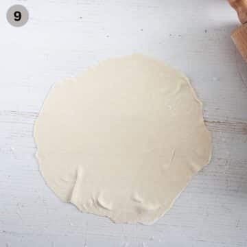 rolled and streched dough for making italian pie on the table.
