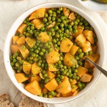 greek peas and potatoes in a bowl with a fork in it.