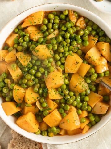 greek peas and potatoes in a bowl with a fork in it.