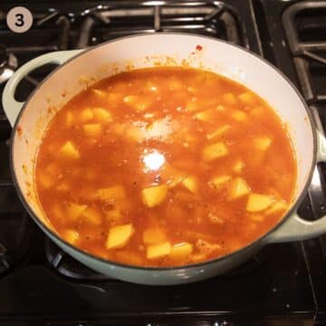 simmering potato and pea stew in a dutch oven on the stove.