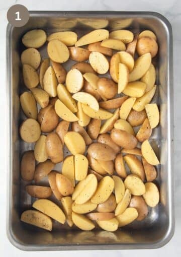 uncooked, halved and quartered fingerling potatoes in a roasting pan.
