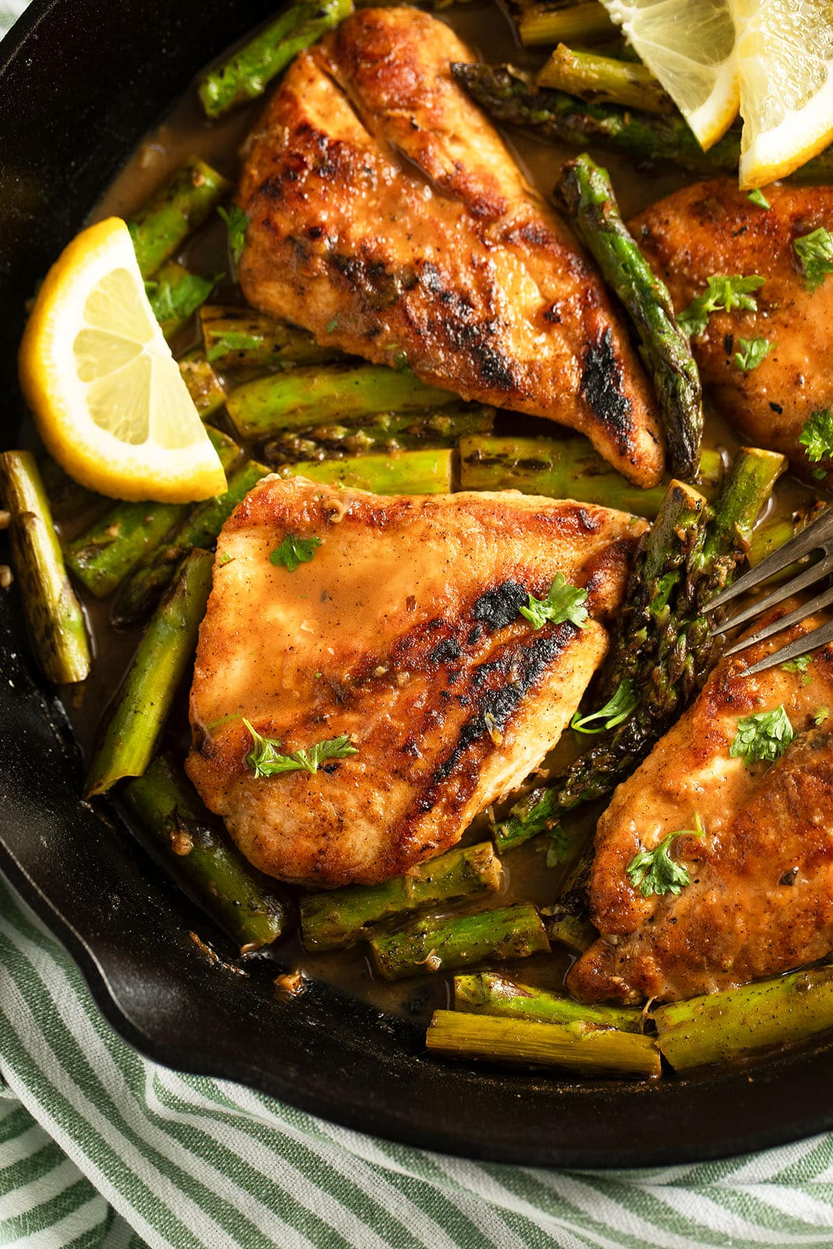 asparagus and chicken breast with lemon slices in a skillet.