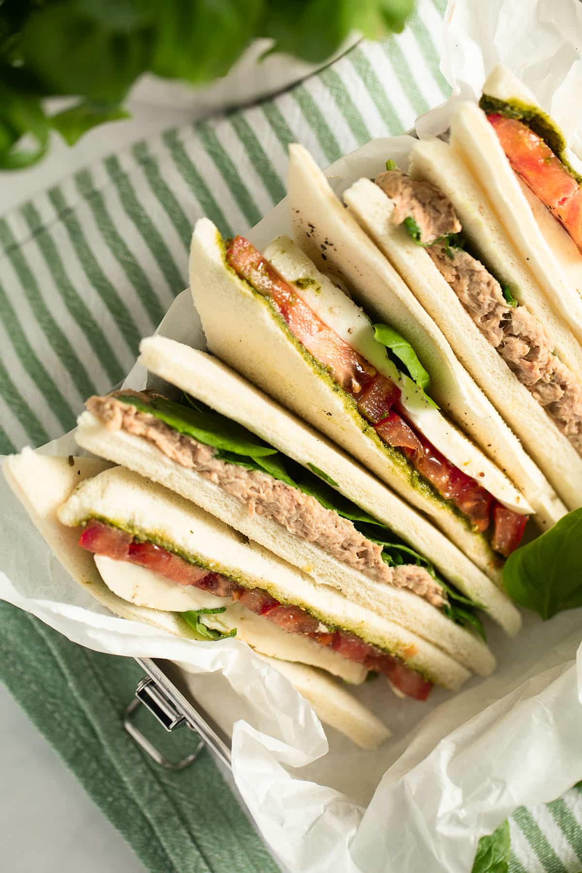 many tramezzini with tuna and tomato and mozzarella filling in a lunch box.