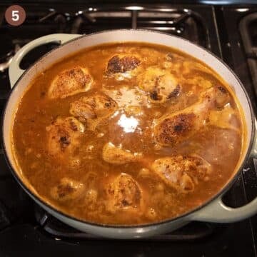 adding stock to a pot with drumsticks and rice.