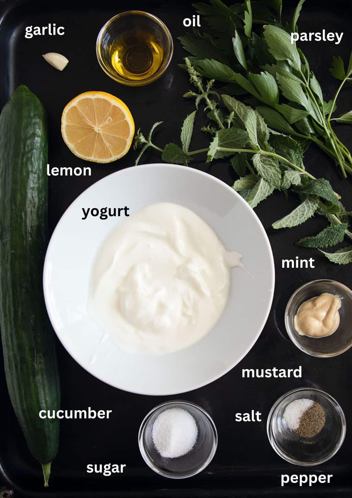 labeled ingredients for making salad with cucumber, yogurt dressing, fresh mint and parsley.