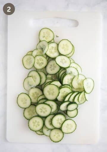 very thinly sliced cucumbers for salad on a cutting board.