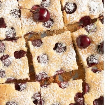 german cherry cake cut into squares and sprinkled with confectioners sugar.