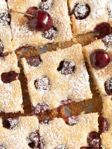 german cherry cake cut into squares and sprinkled with confectioners sugar.