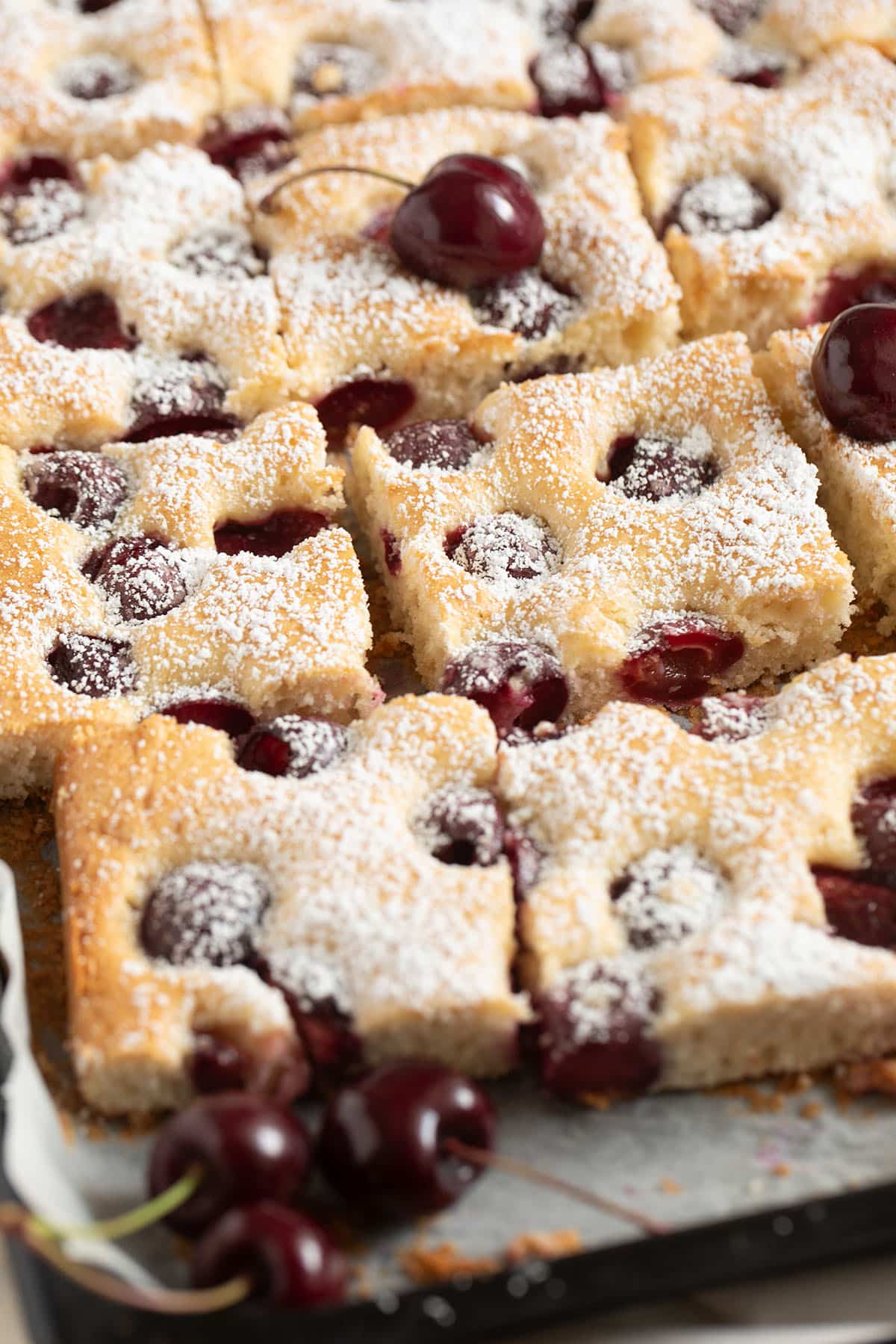 sliced german cherry cake and three fresh cherries.