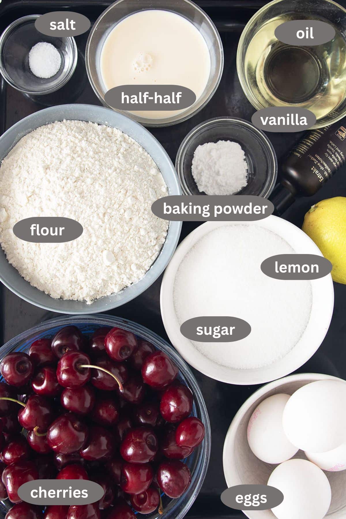 labeled ingredients for making german cake with fresh cherris, flour, sugar, eggs, oil, and lemon.