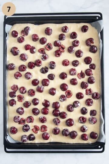 unbaked german cherry cake on a baking sheet .