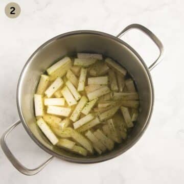 cooked kohlrabi pieces in a pot with vegetable broth.