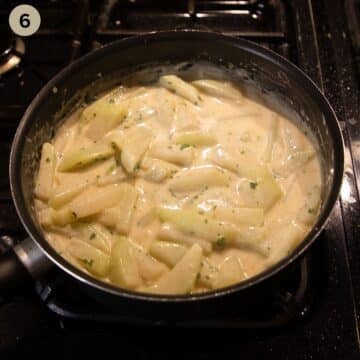 kohlrabi pieces in white sauce in a saucepan.