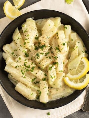 creamy german kohlrabi served in a bowl with lemon wedges.