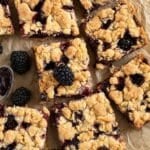 blackberry oat bars cut into small squares and three fresh blackberries.