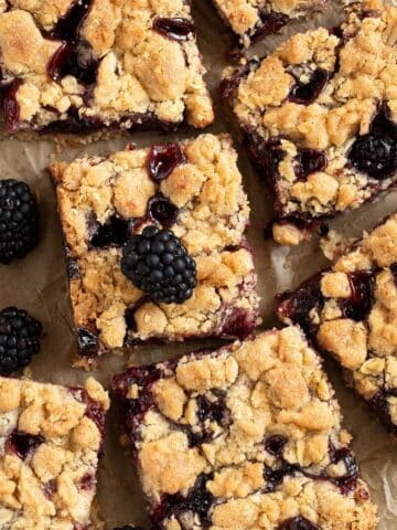 blackberry oat bars cut into small squares and three fresh blackberries.