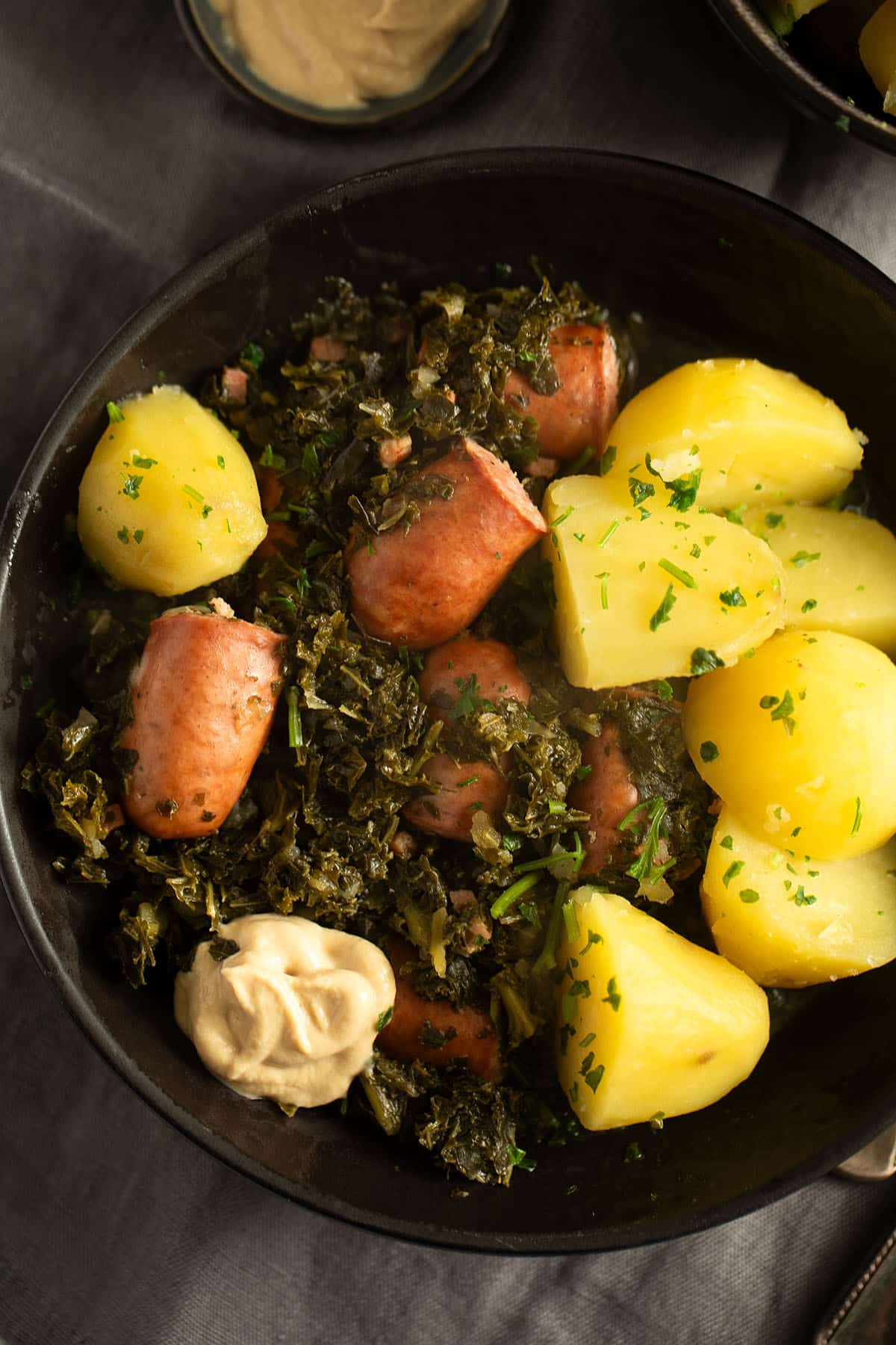 german kale with sausage pieces served with boiled potatoes and mustard