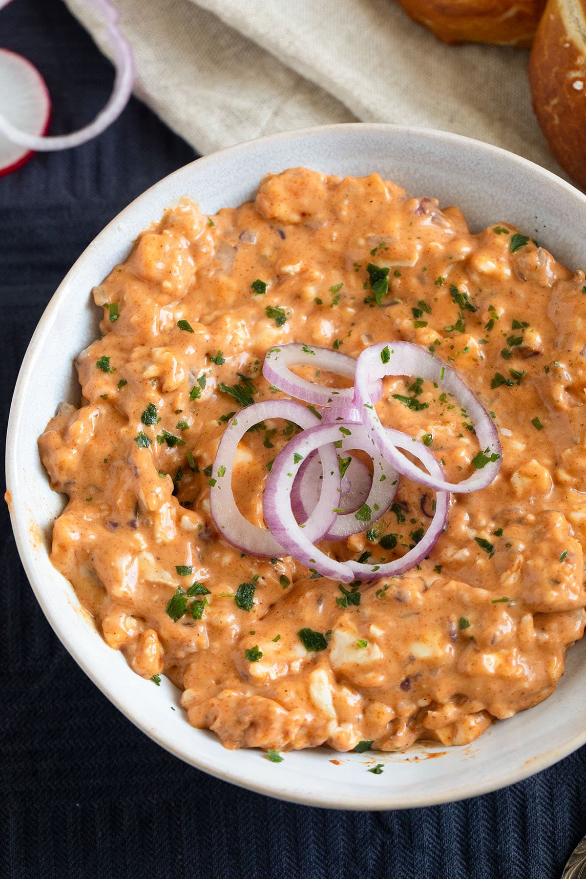 german obatzda garnished with red onion rings in a bowl.