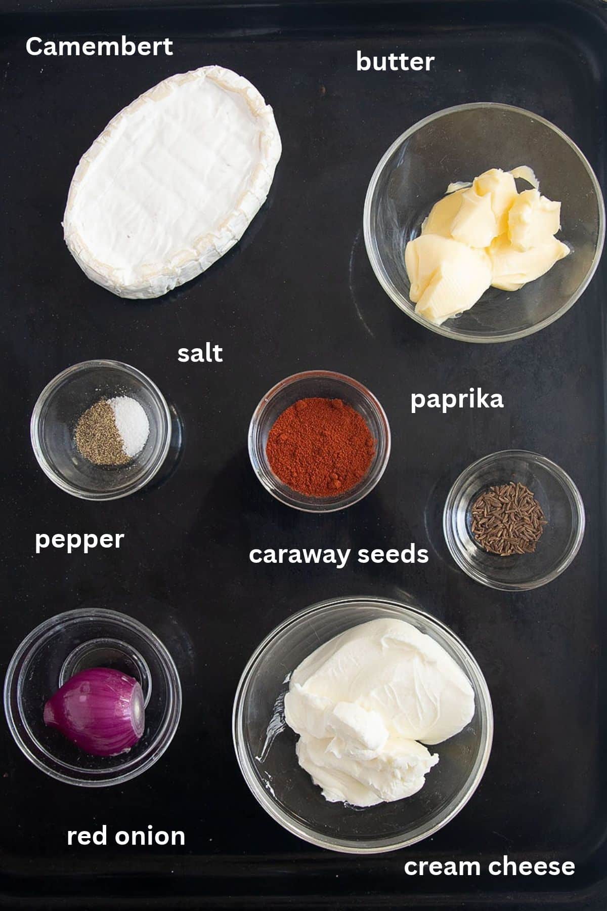 labeled ingredients for making obatzda with camembert, butter, paprika, cream cheese, caraway seeds and red onion.