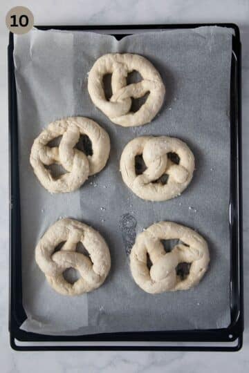 unbaked pretzels sprinkled with salt on a baking dish.