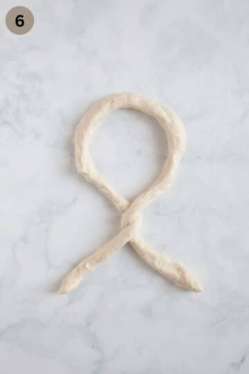 shaping a rope of dough to make german pretzels.