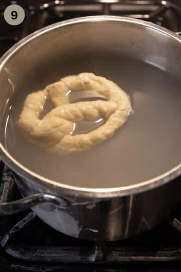 one raw pretzel swimming in a baking soda bath in a large pot.