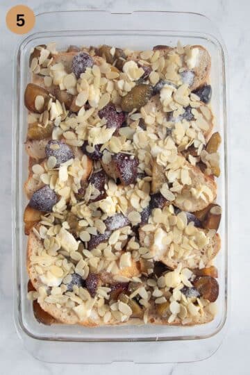 assembled pudding with bread and plums sprinkled with almonds and sugar before baking.
