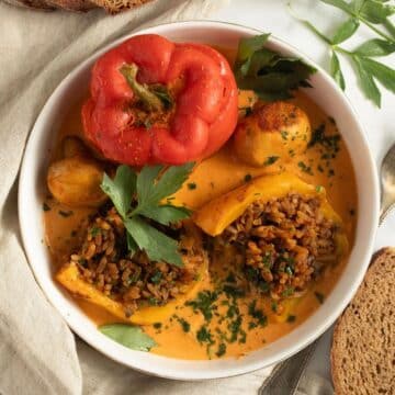 mushroom stuffed peppers in a bowl, one cut to show the filling.