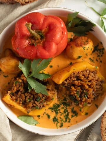 mushroom stuffed peppers in a bowl, one cut to show the filling.