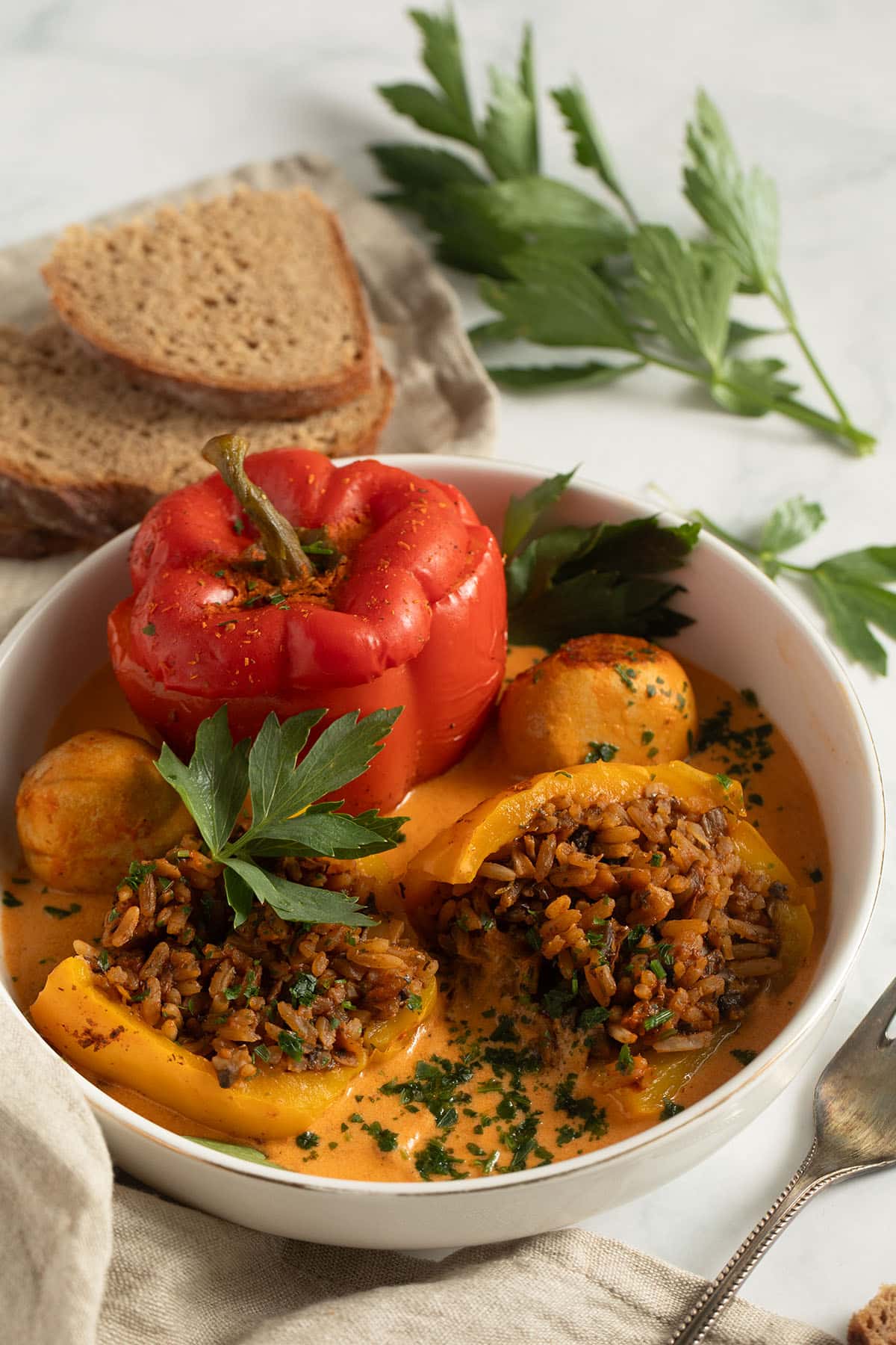a bowl with two mushroom stuffed peppers, one of them cut to show the rice and mushroom filling.