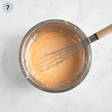 whisking sour cream with flour for making sauce in a bowl.