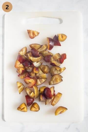 chopped italian plums on a cutting board for making bread pudding.